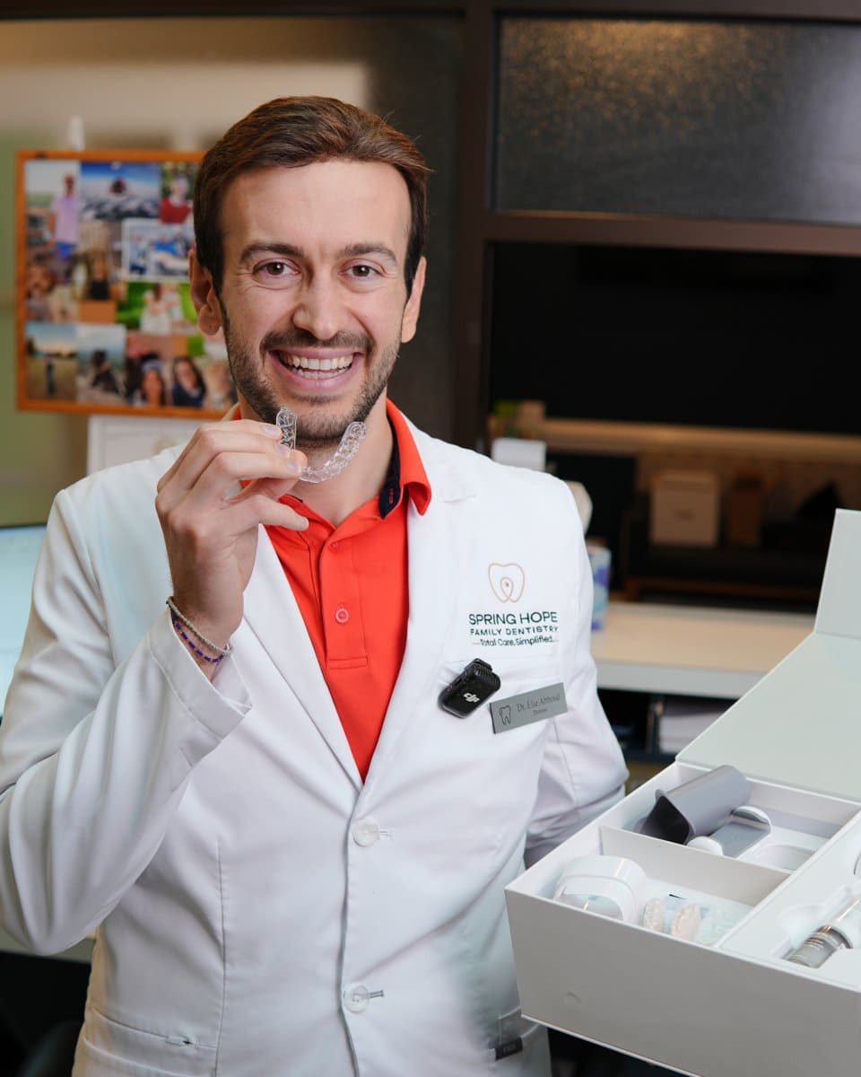 Spring Hope dentist smiling while holding a clear aligner tray