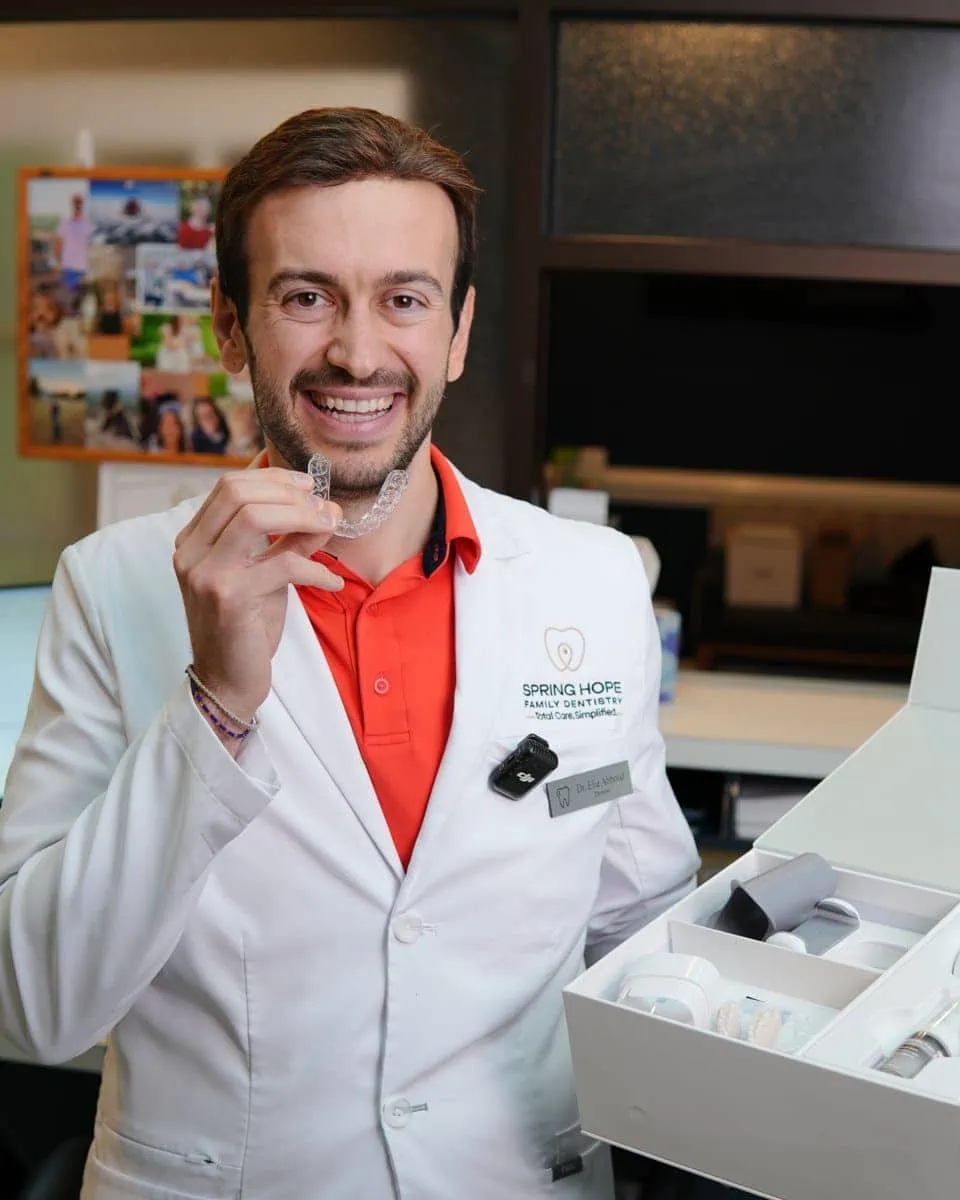 Spring Hope dentist smiling while holding a clear aligner tray