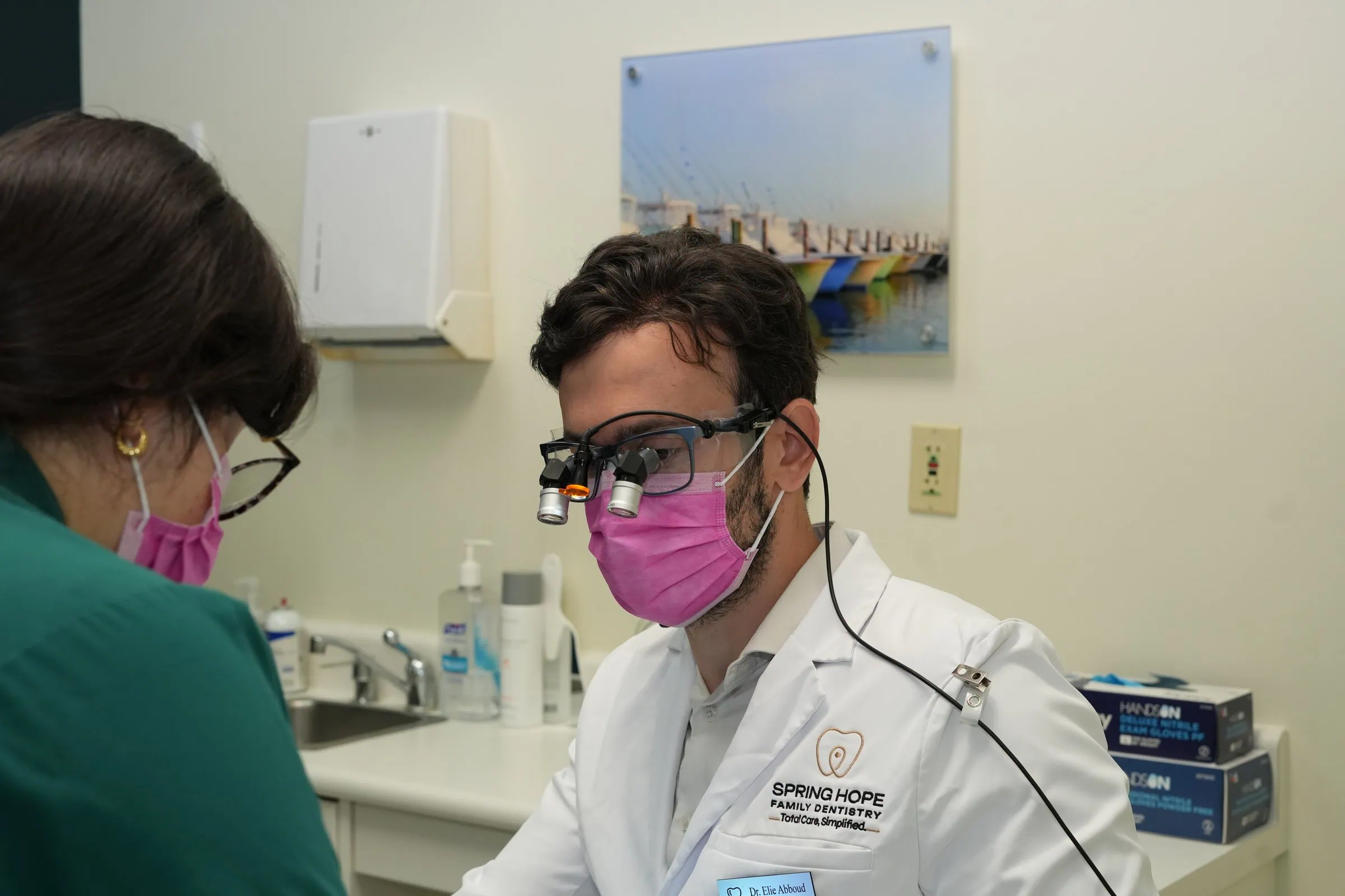 Dr. Elie Abboud wearing loupes talking with a team member