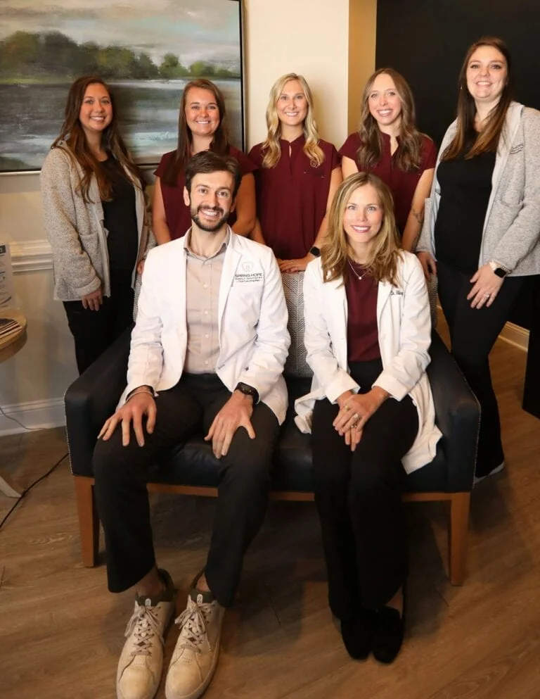 Dr. Abboud and Dr. Hilary seated with the Spring Hope Family Dentistry team in the office lounge